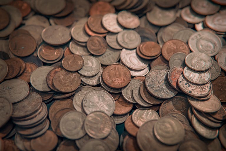 A scattered collection of various vintage coins with copper and silver tones, depicting wealth and currency.